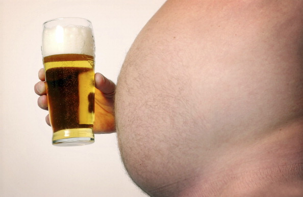 Man with large beer gut holding pint glass full of beer